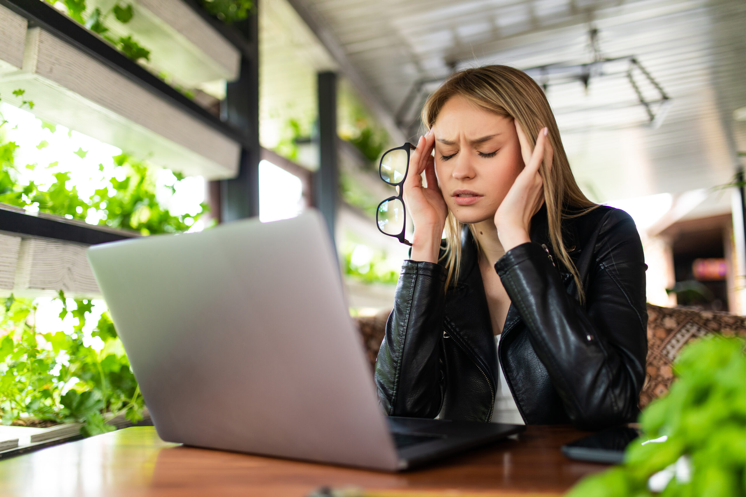 Freelance woman working on her laptop with a headache and her hands on her temples. 