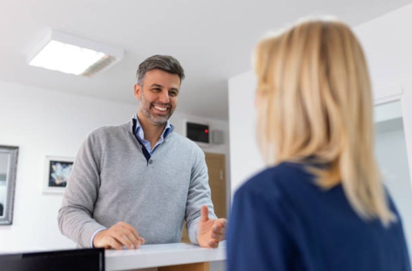 Patient scheduling an appointment with a receptionist at a medical office front desk.