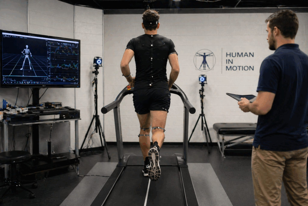 Athlete running on a treadmill with motion sensors while being monitored.