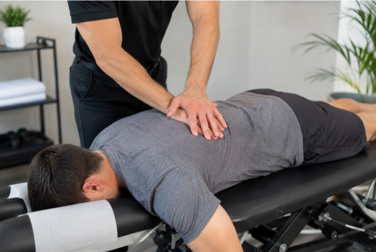 Chiropractor performing a back adjustment on a patient lying face down on a treatment table.